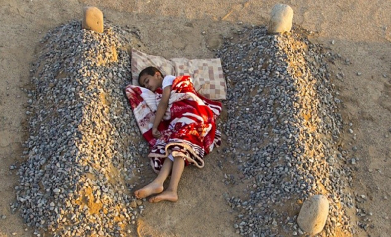 False: A widely shared image shows a Syrian boy sleeping between his parents' graves.